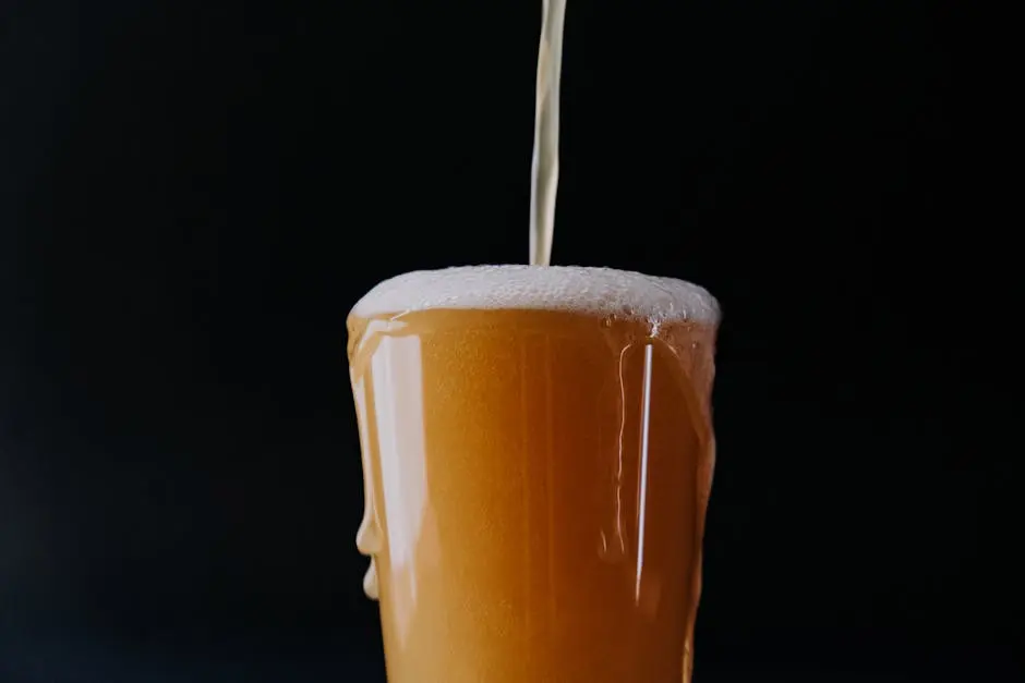 Golden beer overflowing a glass with foam, against black backdrop, close-up view.