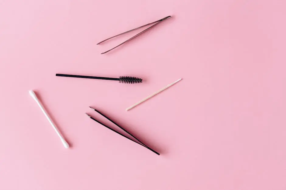 Colorful flat lay of makeup tools featuring tweezers and brushes on a pink background.