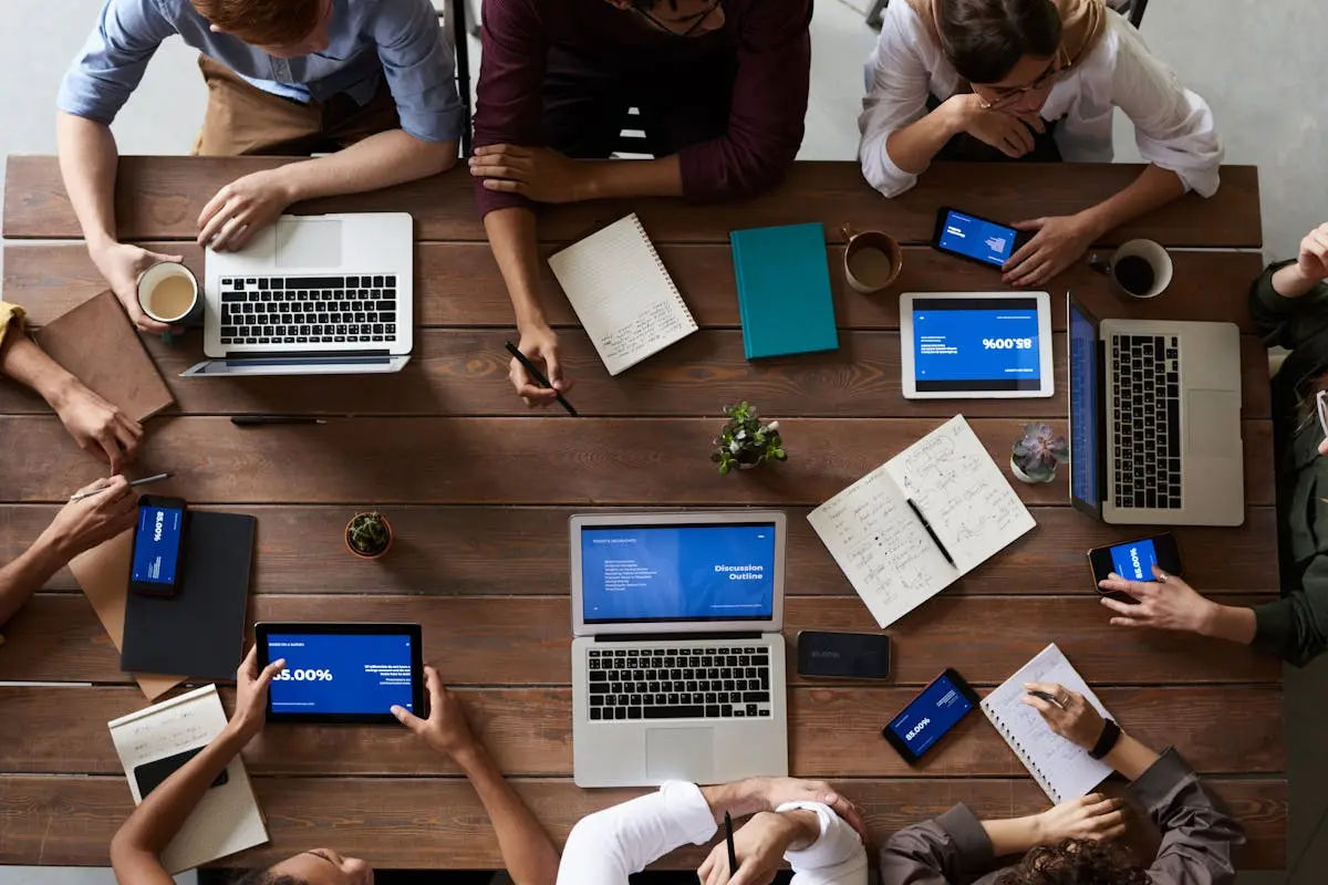 Overhead view of a sales training team in a business meeting using laptops and tablets.