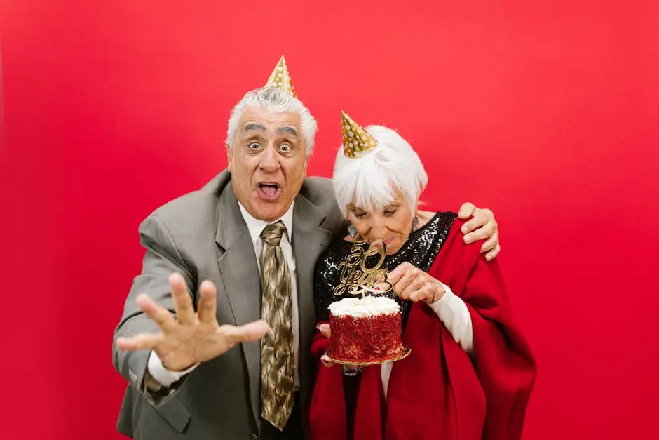 Joyful elderly couple celebrating their 50th anniversary with a cake and party hats in a festive setting.