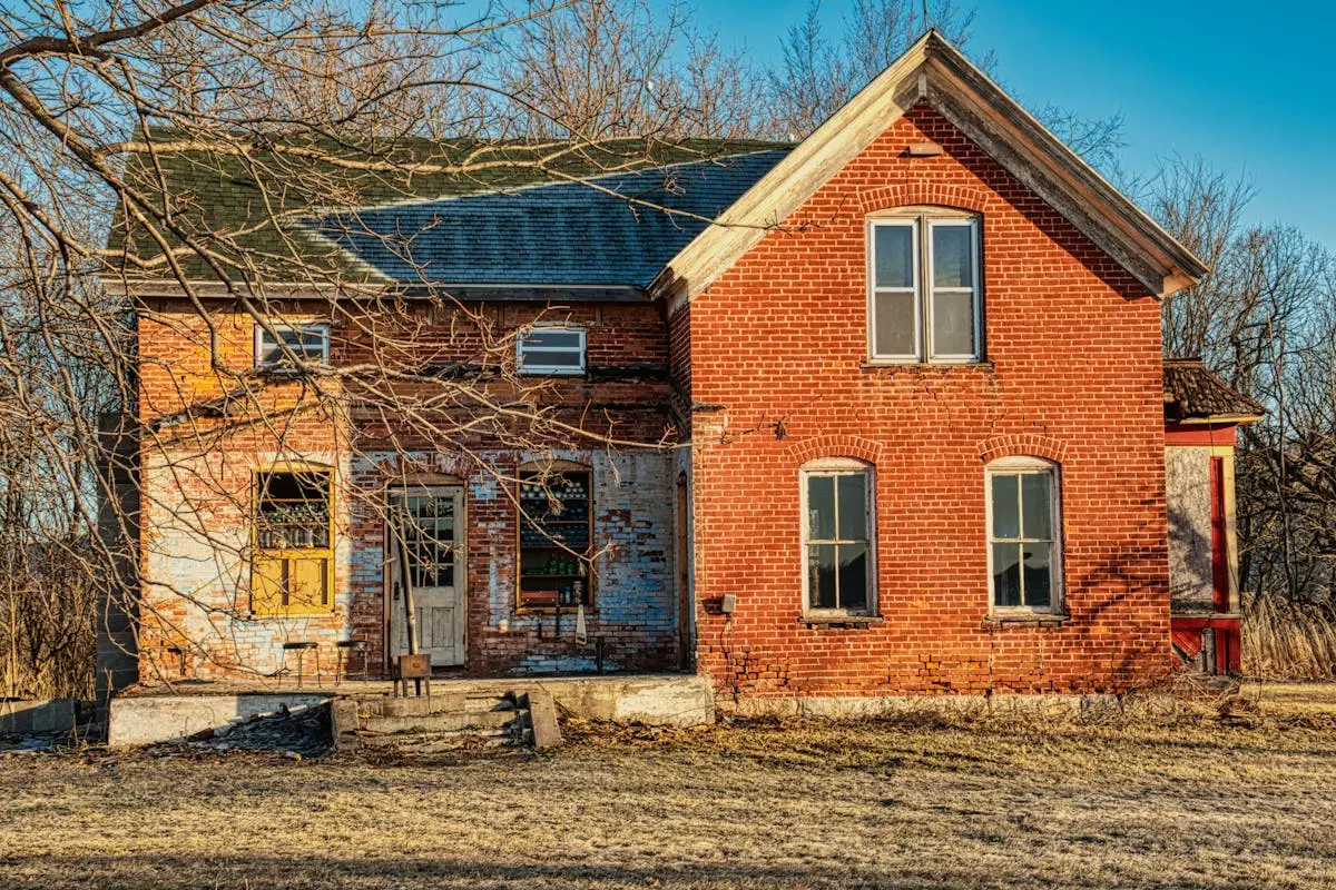 Rustic abandoned brick house exterior in Kellogg, MN during late fall.