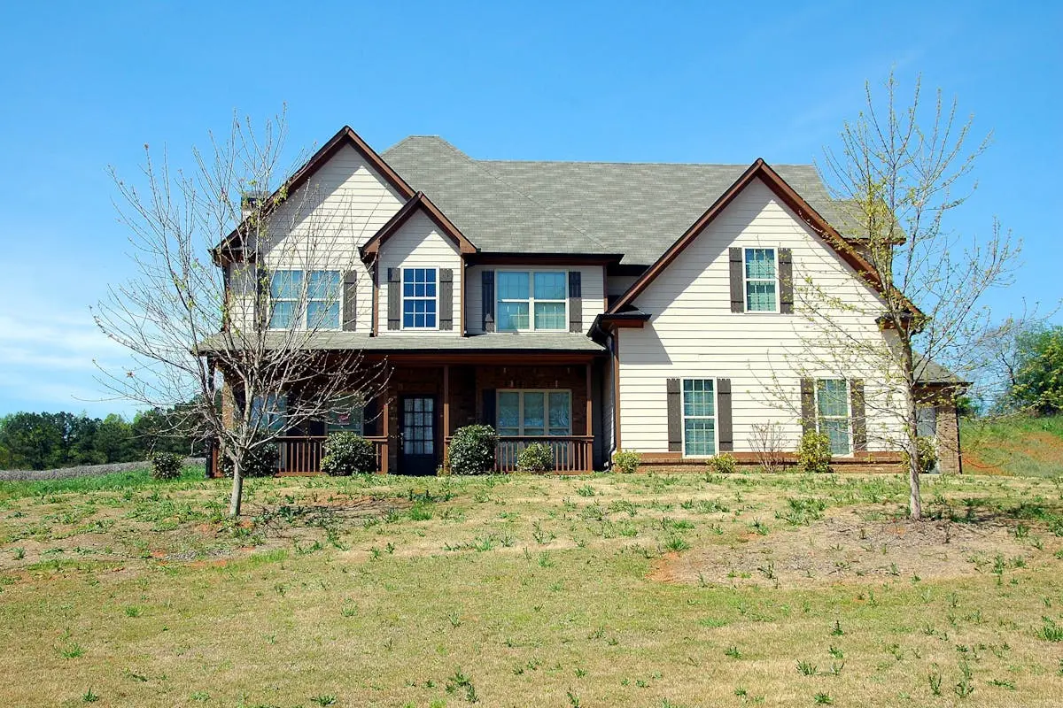 Beautiful two-story suburban home with a spacious lawn under clear blue skies.