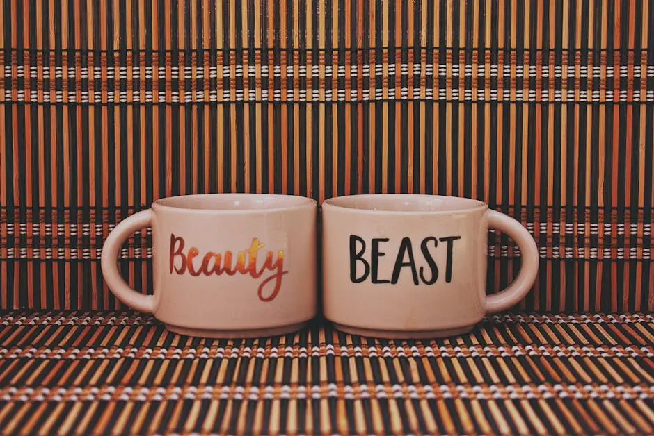 Two coffee mugs labeled ‘Beauty’ and ‘Beast’ set against a striped, artistic background.