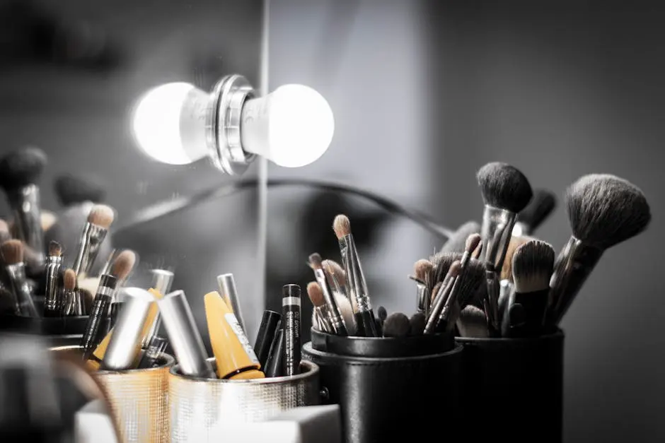 Close-up of makeup brushes and light bulb reflection creating a studio vanity atmosphere.