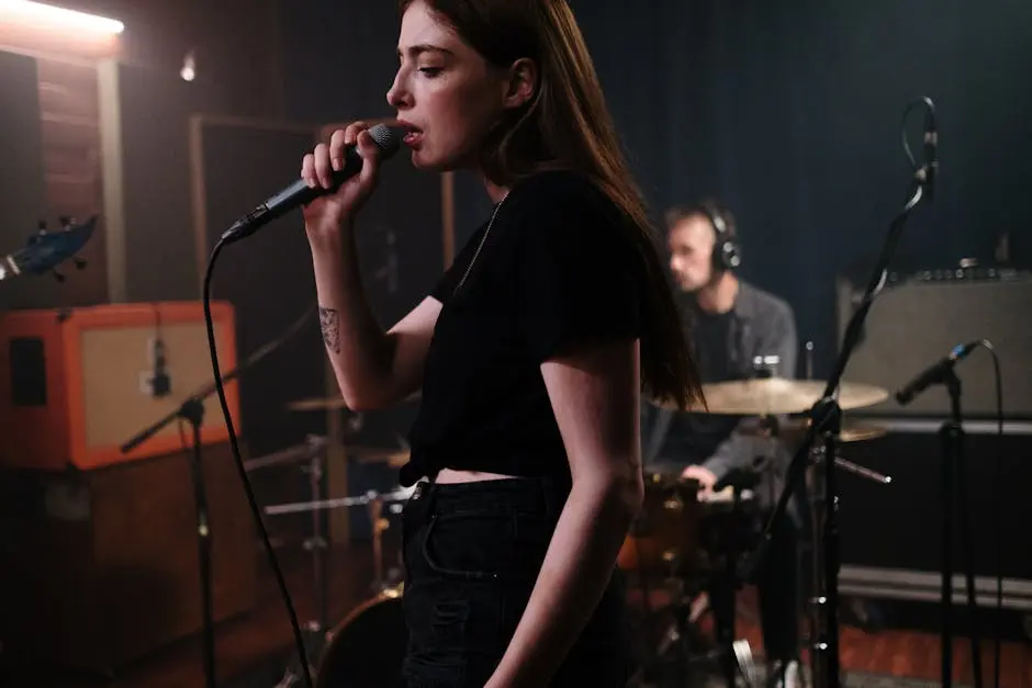 A female singer passionately performs during a band practice session in a music studio.