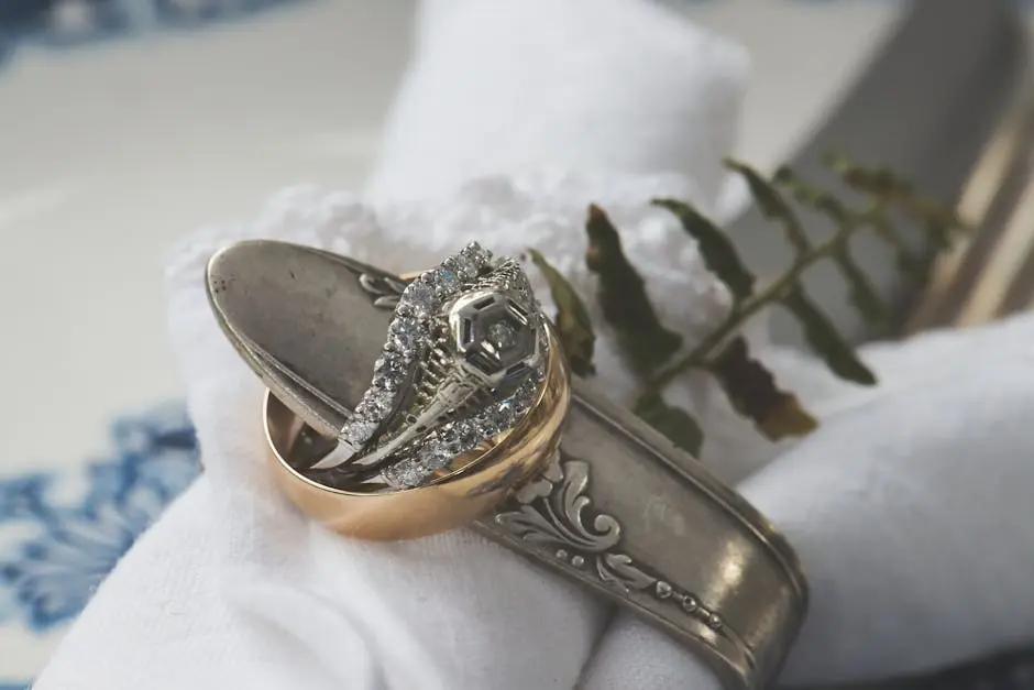 Close-up of silver and gold rings with fern on decorative table setting, evoking luxury and elegance.