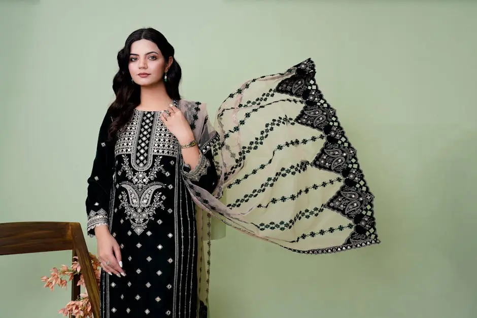 Stylish woman posing in a beautifully embroidered black dress with intricate details.