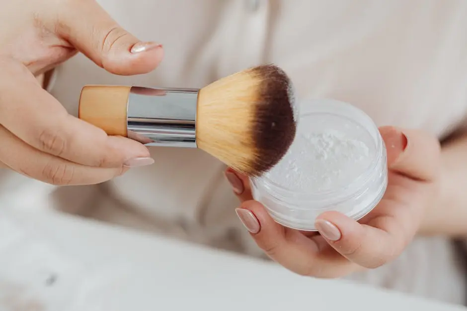Close-up view of a hand applying face powder with a makeup brush, perfect for beauty and lifestyle concepts.