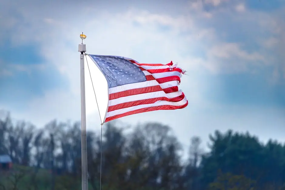 A weathered American flag waves against a vibrant blue sky, symbolizing resilience in Pittsburgh.