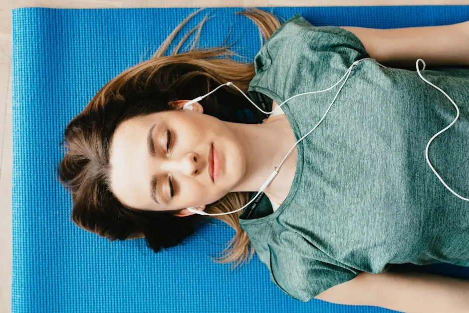 Young woman meditating with closed eyes on a yoga mat, listening to music.