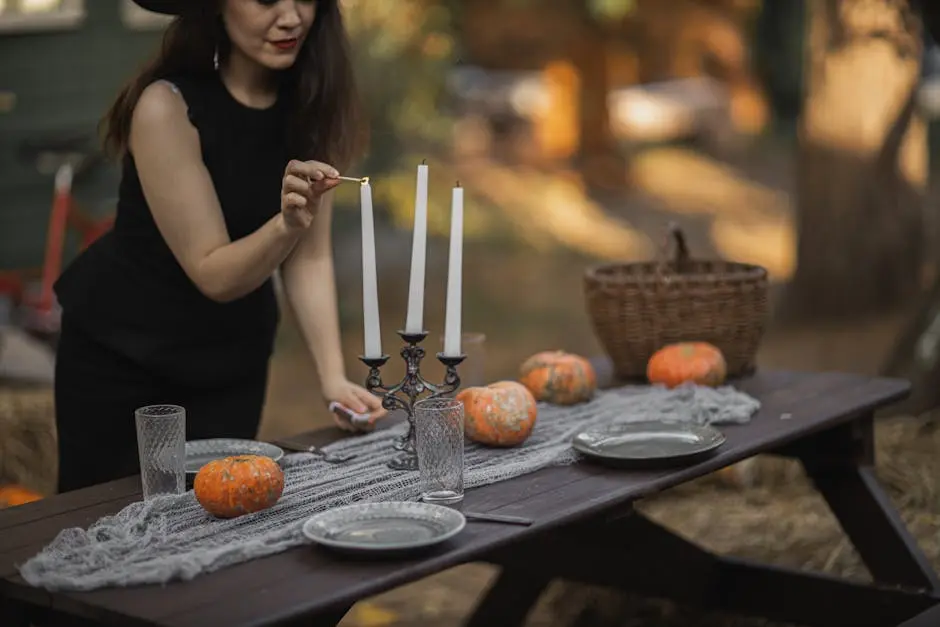 Elegant autumn scene with a woman lighting candles on a pumpkin-themed outdoor table setup.