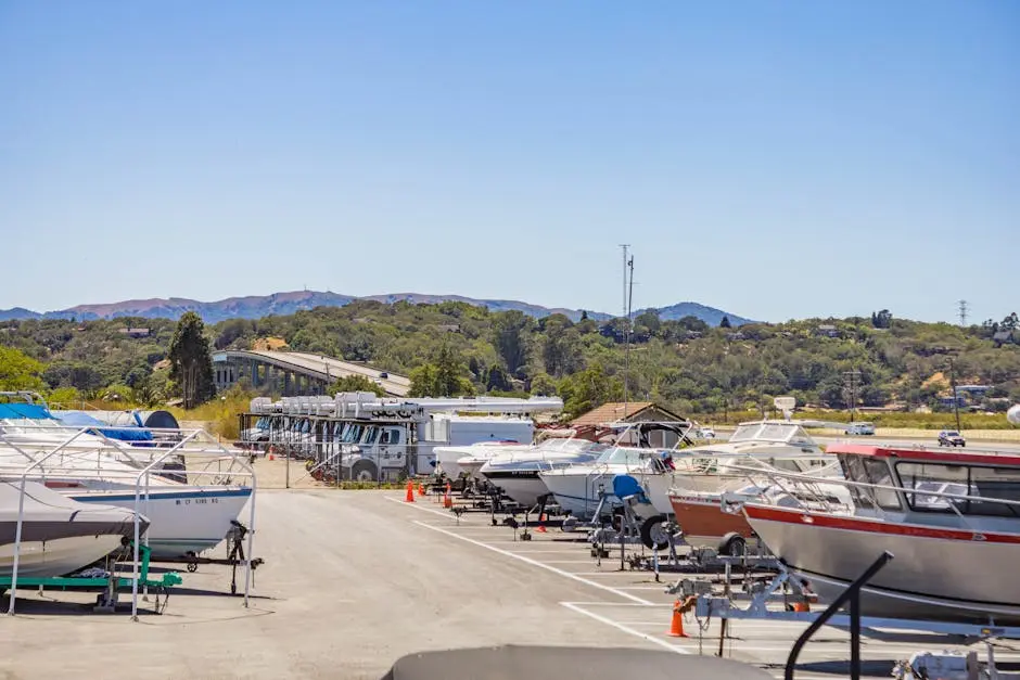 A scenic marina with boats and RVs parked under a clear blue sky, surrounded by greenery.
