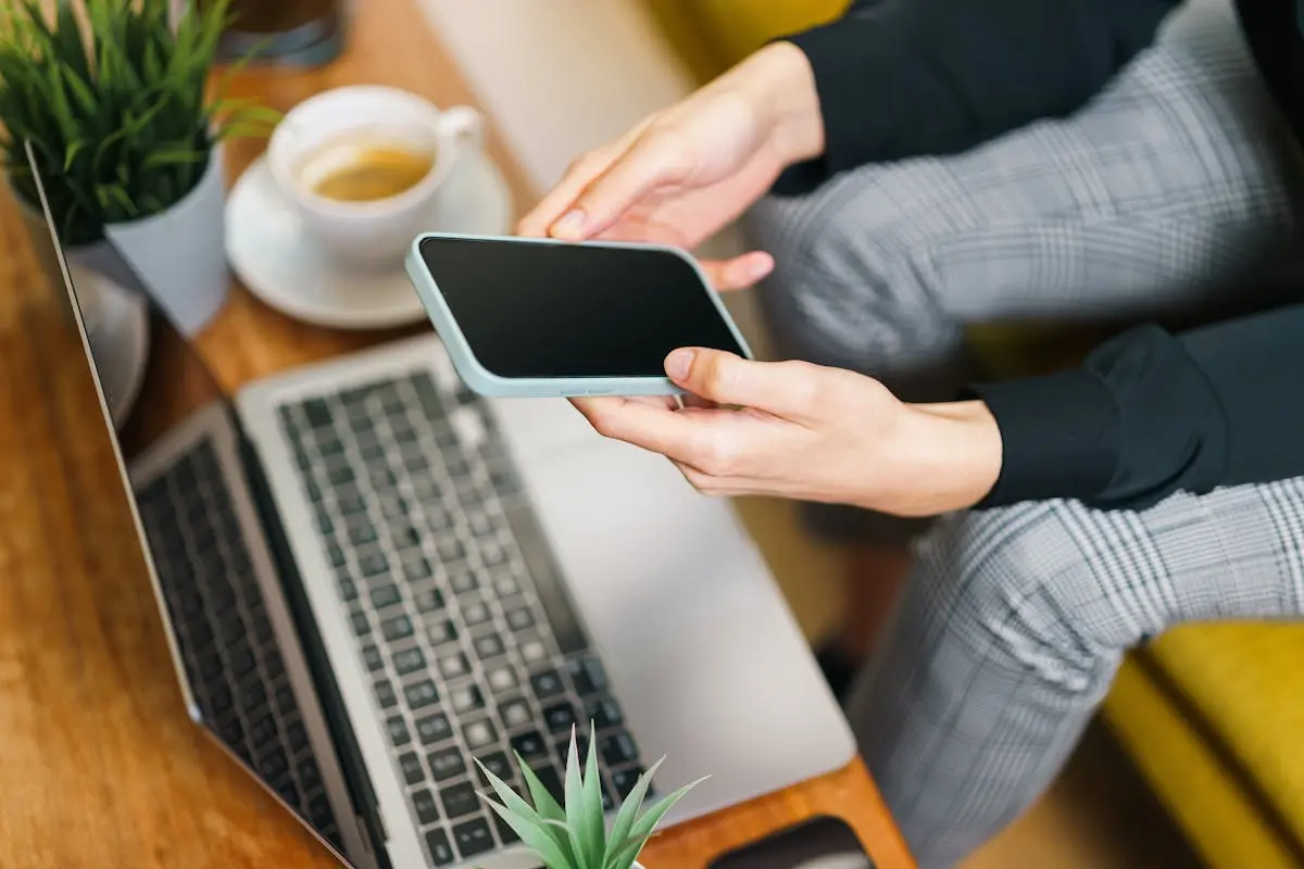 Person holding phone at restaurant table with coffee by the side