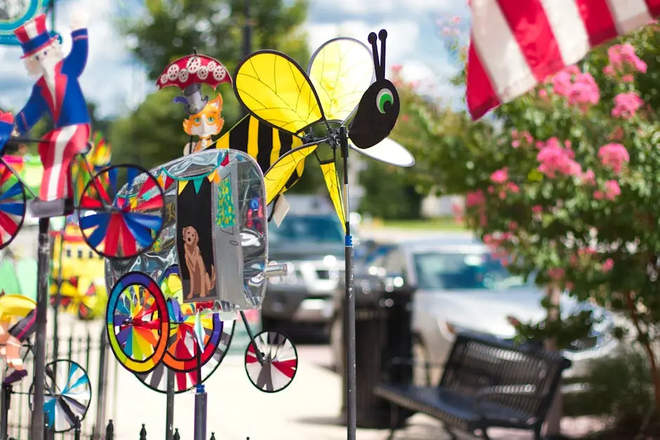 Brightly colored wind spinners on display in an outdoor garden setting alongside flowers and an American flag.