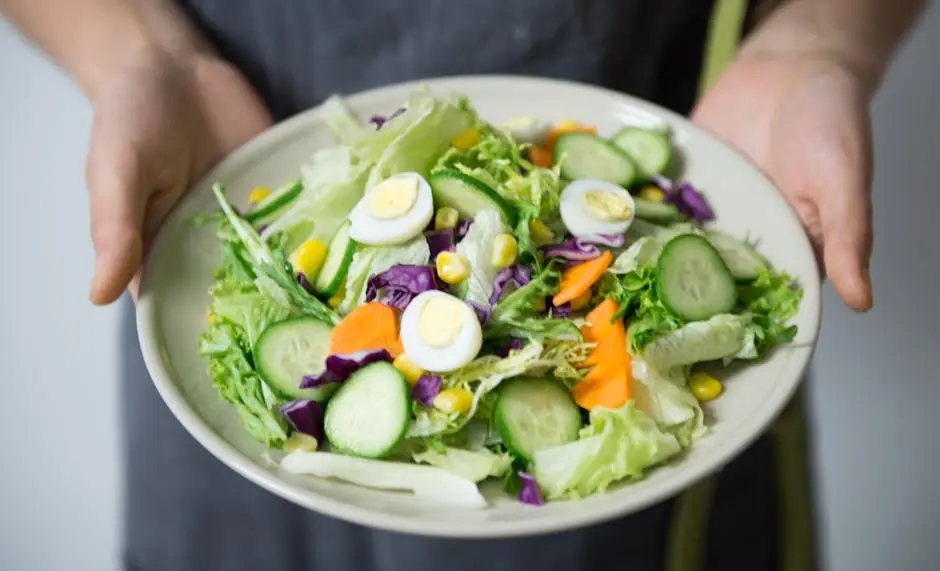 Freshly prepared salad with cucumber, lettuce, carrots, and egg slices presented on a plate.