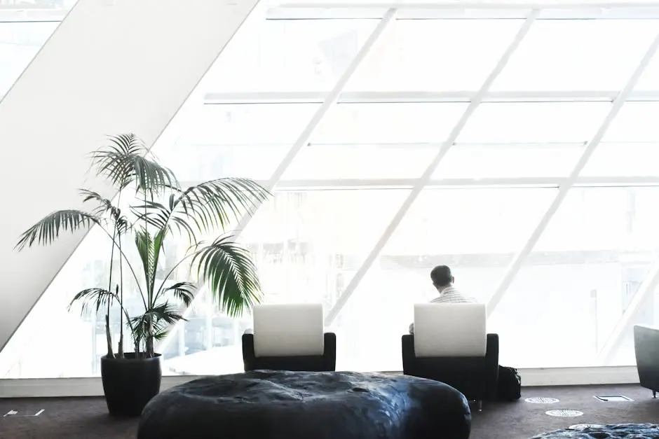 Spacious modern lounge with minimalist decor, featuring large windows and stylish seating.