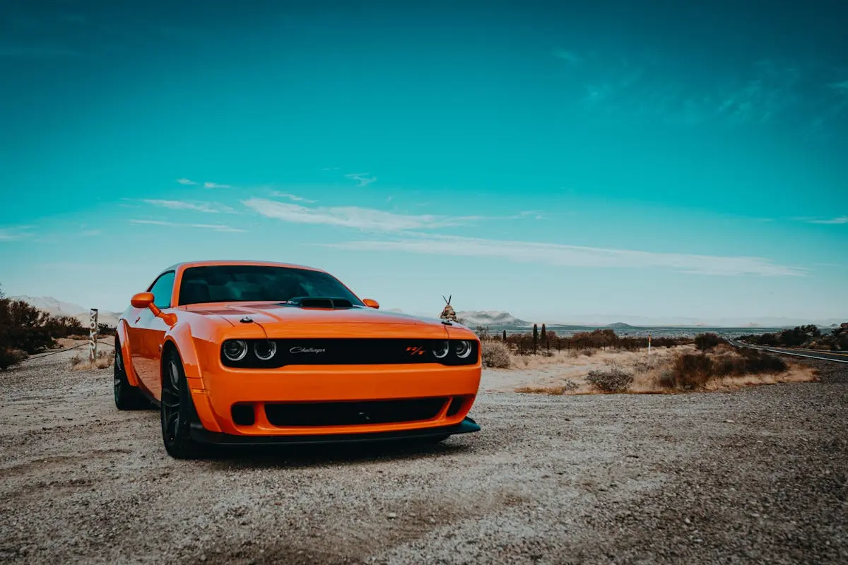 Orange Dodge Challenger sports car parked on a scenic Arizona desert road.