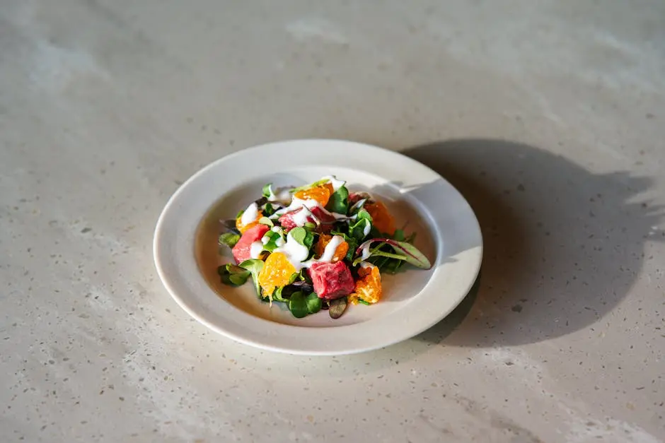 Vibrant salad with oranges, greens, and creamy dressing on a white plate.