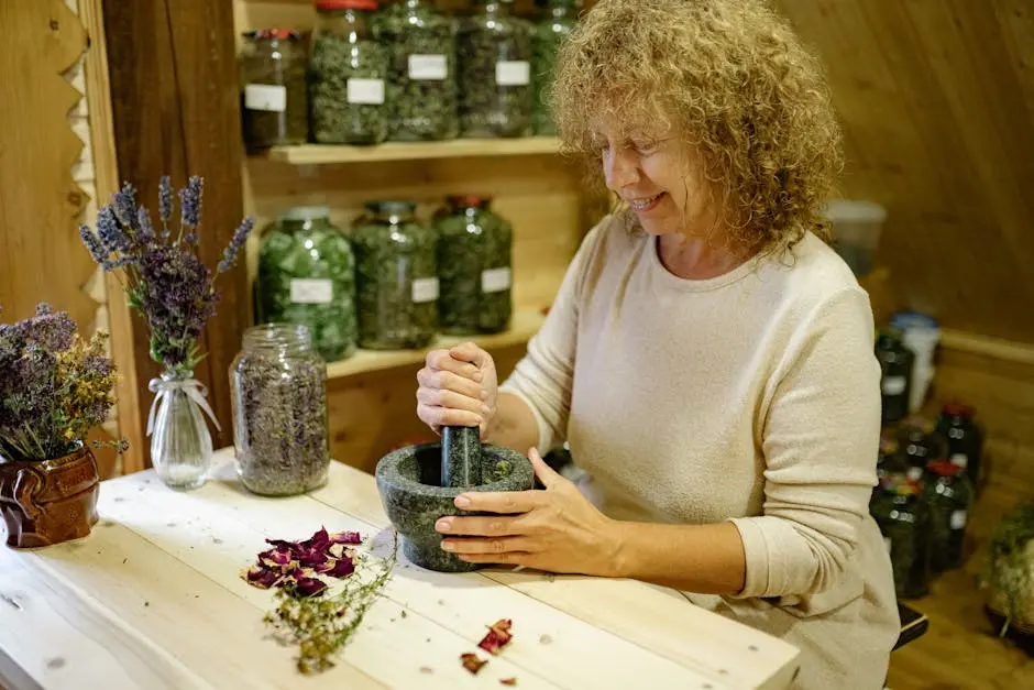 Smiling woman uses a mortar and pestle to make herbal remedies in a cozy home setting.