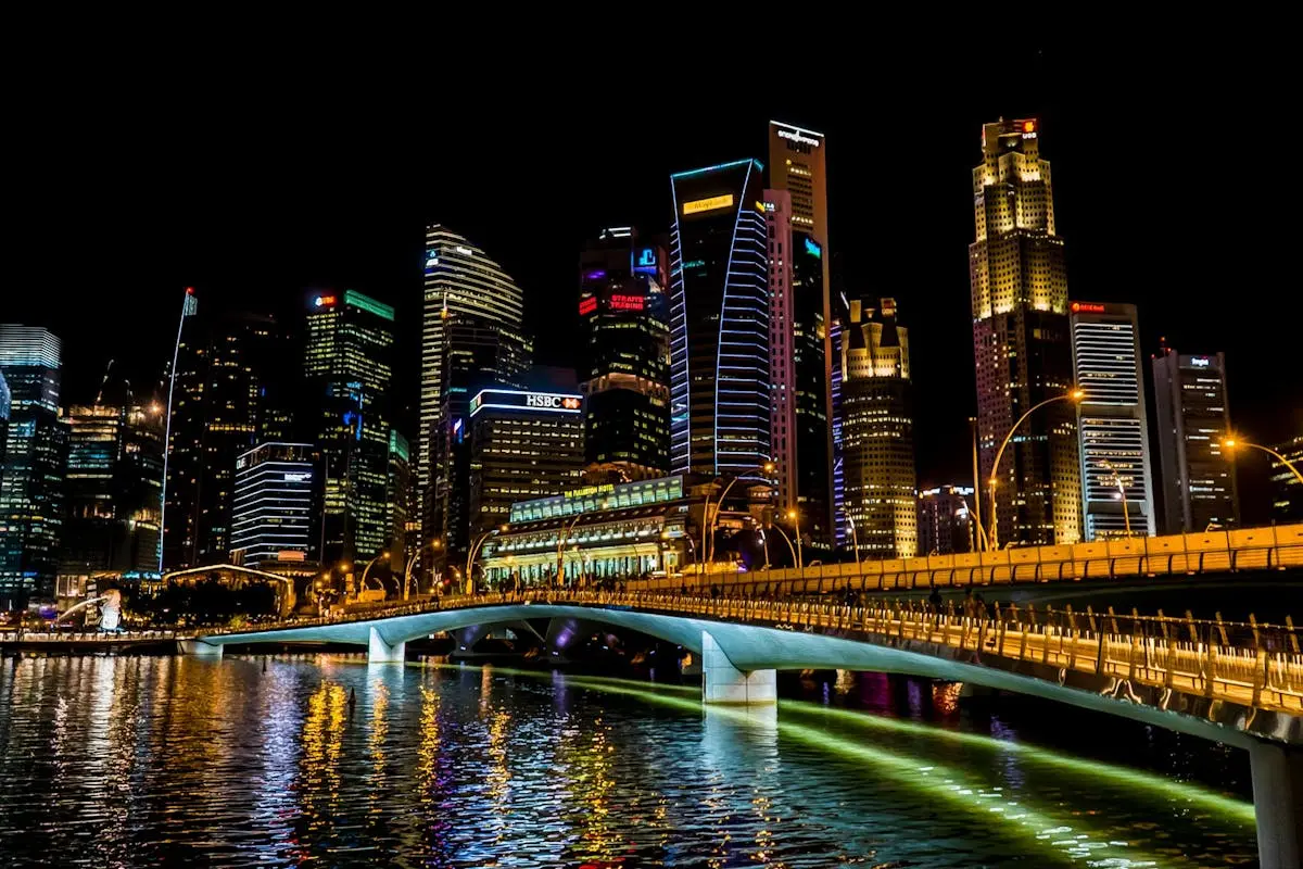 Stunning Singapore cityscape featuring vibrant skyscrapers, illuminated bridge, and reflections over the river at night.