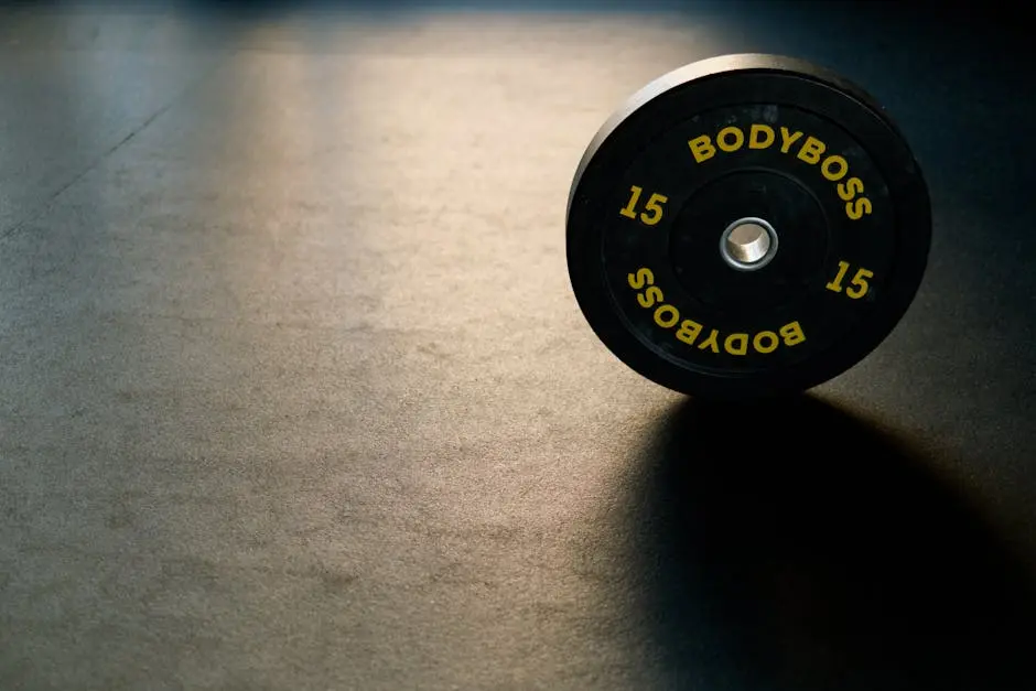 Black BodyBoss weight plate on gym floor, ideal for fitness and workout themes.