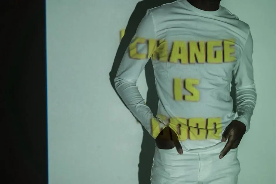 A man in white with text CHANGE IS GOOD projected on his shirt in a studio setting.