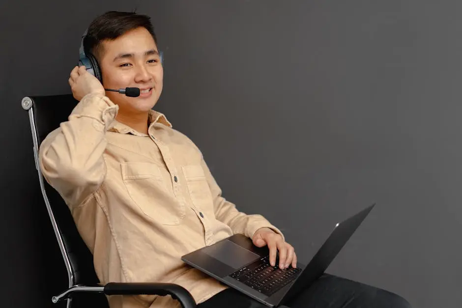 Smiling customer service agent using a laptop and headset indoors.