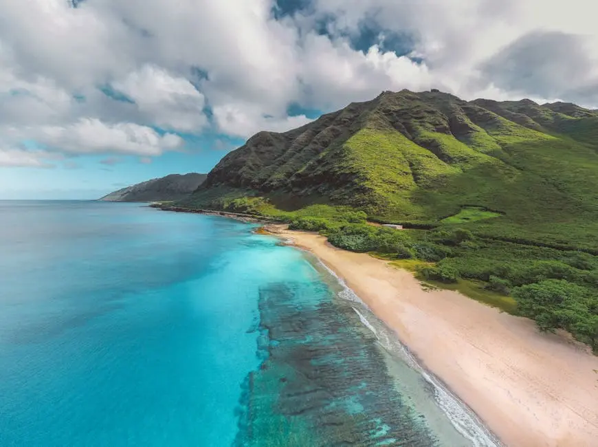 Stunning aerial view of a vibrant Hawaiian coastline with lush mountains and crystal-clear waters.