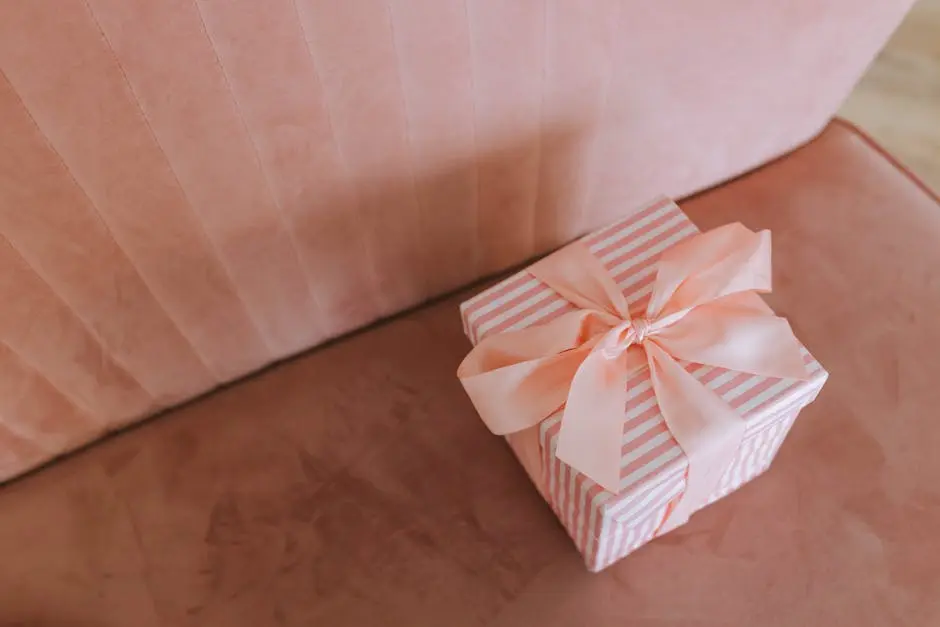 A beautifully wrapped gift box with a pastel ribbon on a plush pink couch, perfect for special occasions.