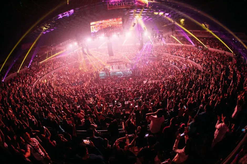 Vibrant crowd enjoying a live concert in a bustling Manila arena at night.