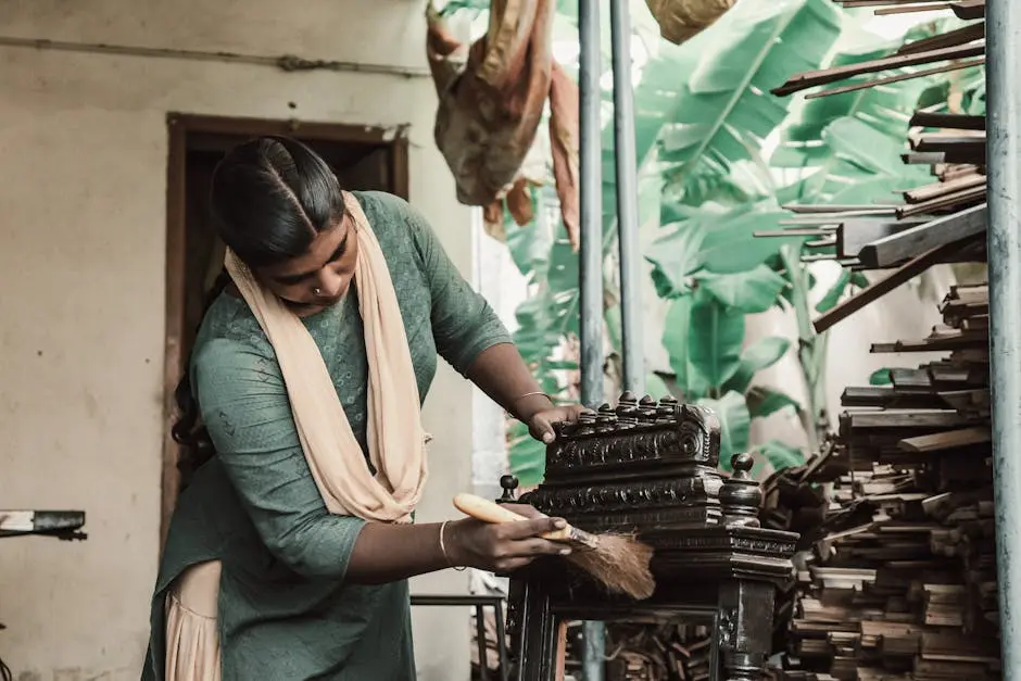 South Asian woman cleaning wooden furniture in an indoor workshop setting.