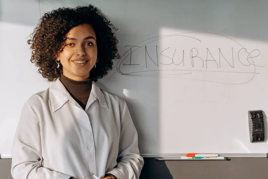 African American woman smiling in office setting with a whiteboard displaying &lsquo;Insurance&rsquo;.