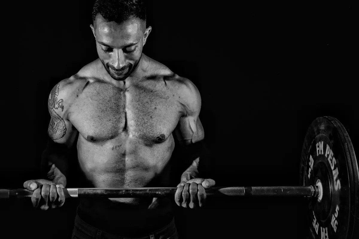 Dramatic black and white photo of a muscular man lifting weights, focusing on strength.
