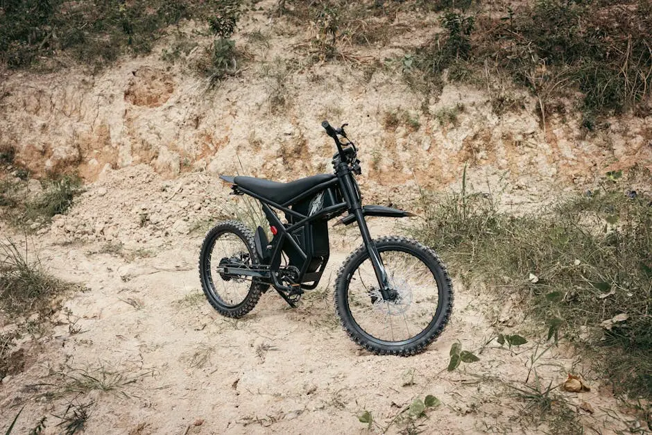 A modern black electric dirt bike parked on rough terrain, ready for an adventurous ride.