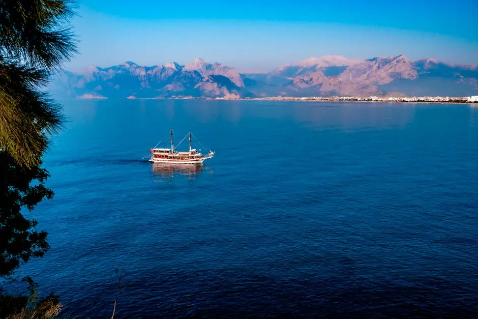 Cruise ship sailing on a serene blue sea with mountainous backdrop, perfect for travel inspiration.