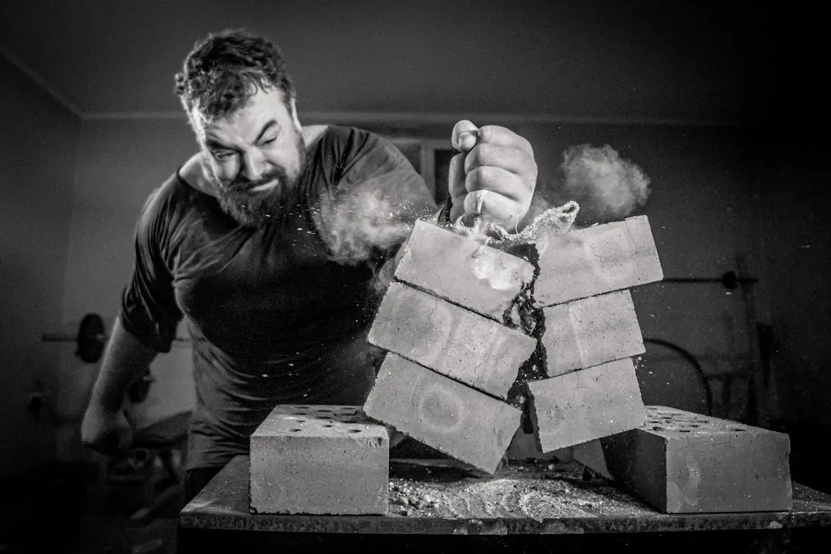 Dynamic image of a man smashing bricks with bare hands indoors.