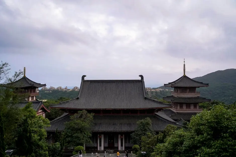 Breathtaking view of a traditional Buddhist temple amid lush hills under a cloudy sky.