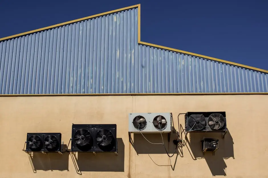 Exterior view of industrial air conditioning units mounted on a warehouse wall under clear blue sky.