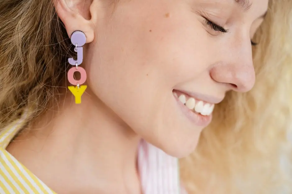 Close-up of a smiling woman wearing pastel-colored ‘JOY’ earrings, embodying happiness.