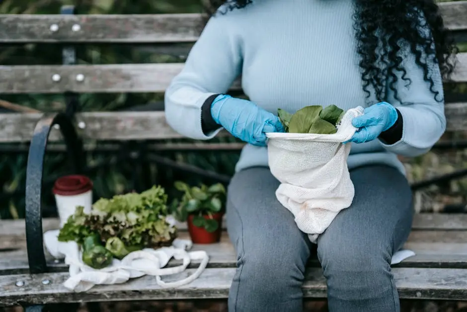A woman wearing gloves sits on a bench with an eco-friendly grocery bag and fresh produce.