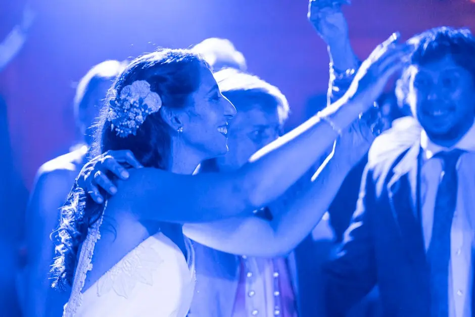 A bride celebrates on the dance floor, surrounded by guests at a lively wedding party.