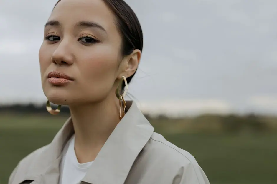 Stylish woman posing outdoors wearing Prom Earrings coat and gold earrings.