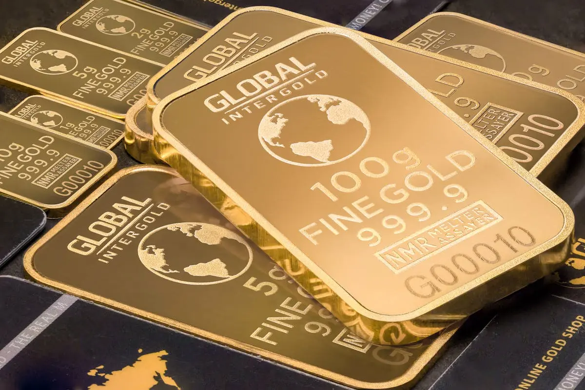 A detailed shot of gold bars labeled Global Intergold as a symbol of wealth and business acquisitions.