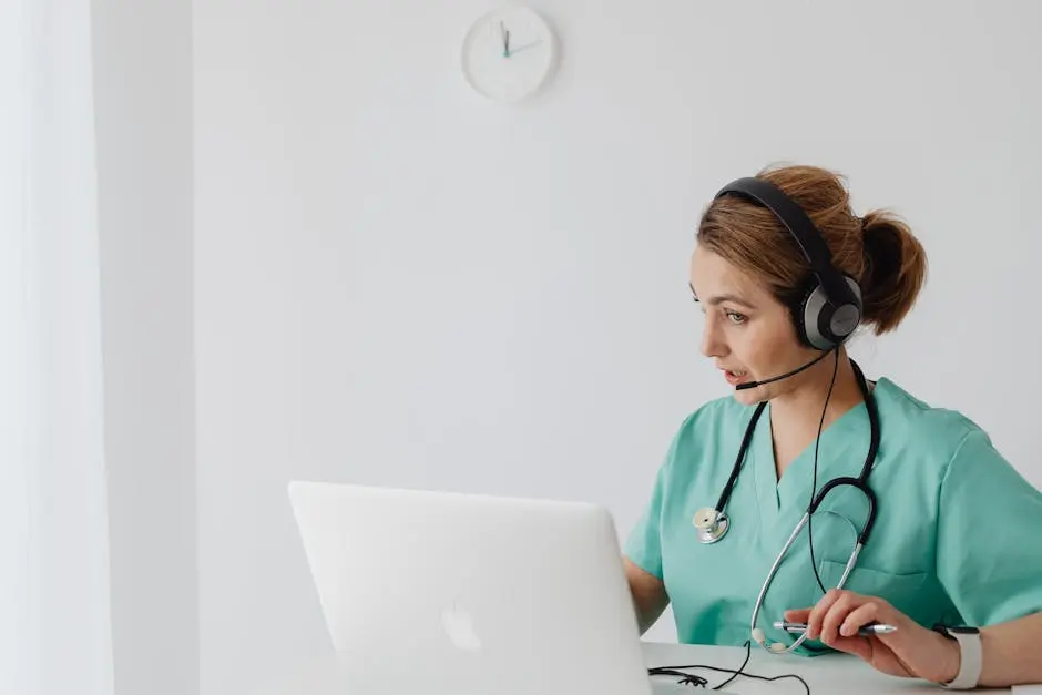 Medical professional using laptop and headphones for an online consultation in a modern office.