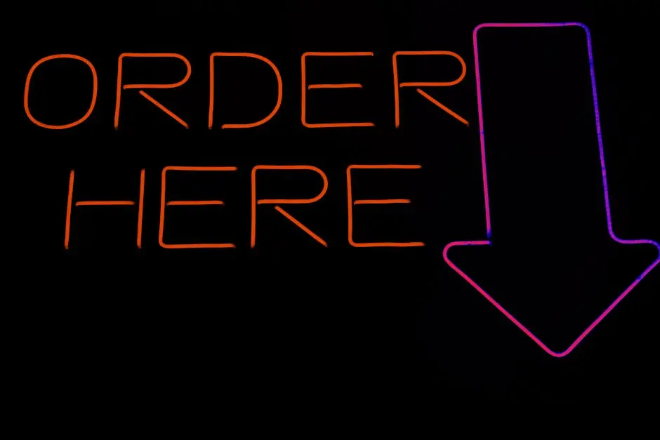Bright neon ‘Order Here’ sign with an arrow, perfect for restaurants or cafes.