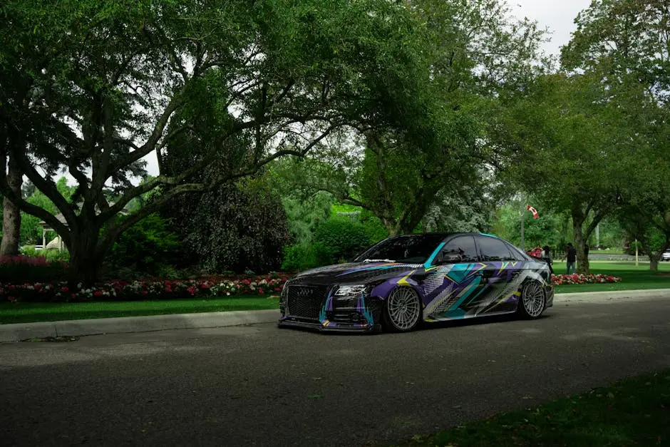 A custom sports car with unique graphics parked under lush greenery in a scenic urban park in Toronto.