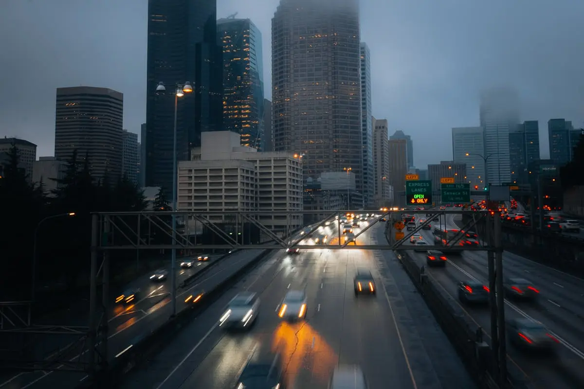 A foggy evening view of Seattle’s skyscrapers with blurred car lights on the highway.