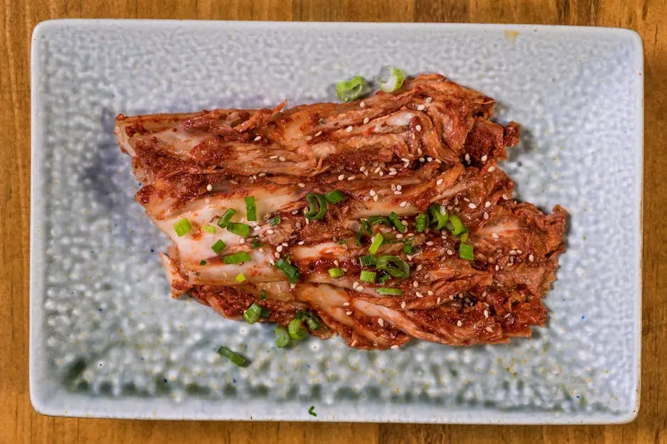 Close-up of fresh homemade kimchi garnished with green onions and sesame seeds on a textured plate.