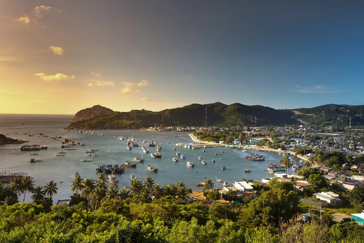 Picturesque coastal landscape with boats and hills during sunset, showcasing a serene seaside ambiance.