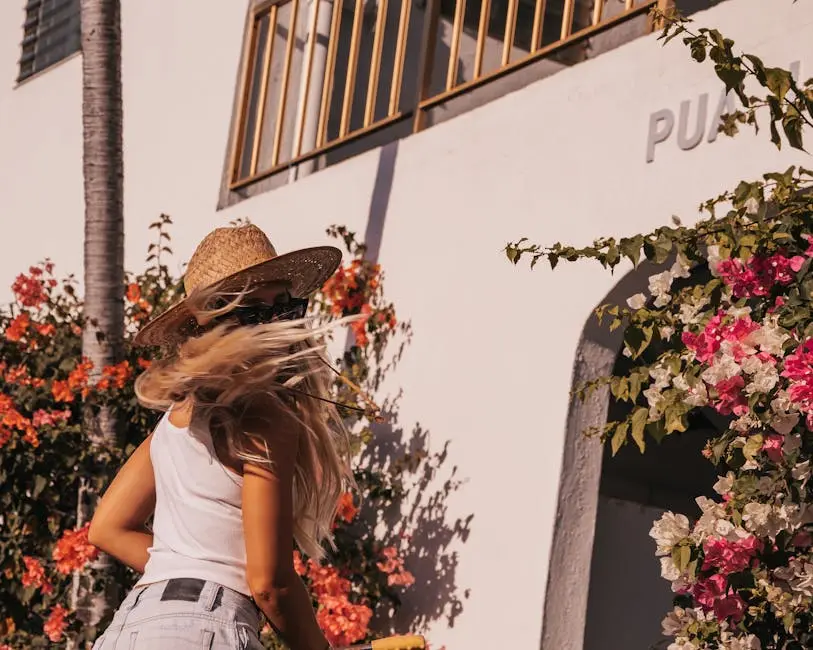 A woman in a straw hat enjoys a sunny day next to colorful flowers. Honolulu, HI.